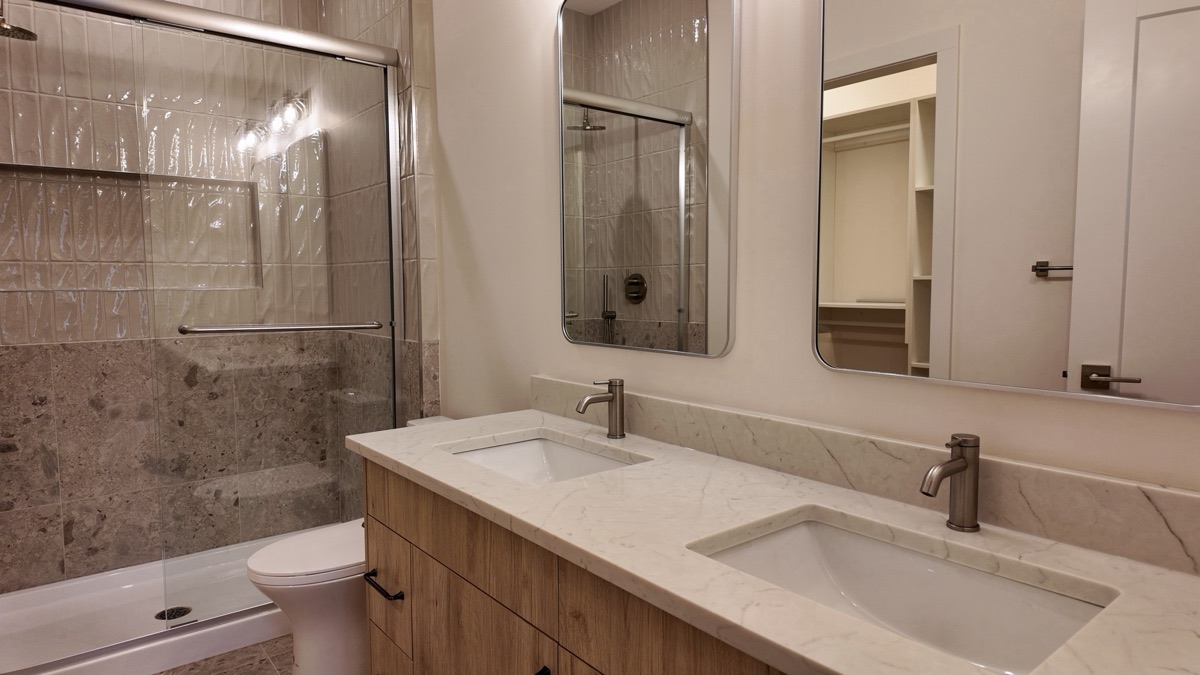 Primary ensuite with a double vanity and glass shower.